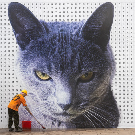 Un trabajador limpia la acera delante del retrato de un gato en Hong Kong