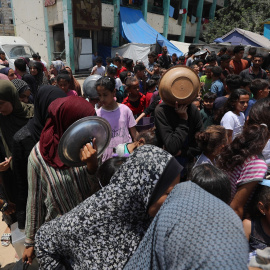 Los palestinos esperan en largas colas para recibir ollas de comida distribuidas por organizaciones humanitarias.