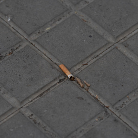 Una colilla de un cigarro tirada en la acera.