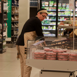 Una treballadora reposant un expositor de menjar