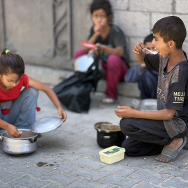Niños palestinos reciben comida en un centro de Nuseirat.
