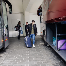 Un joven coloca su equipaje en el maletero de un autocar.