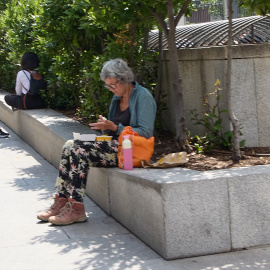 Una mujer se sienta a descansar en el centro de Madrid y mirar su teléfono móvil.