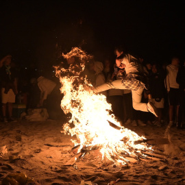Una persona salta una hoguera en la Noche de San Juan, en A Coruña, Galicia.