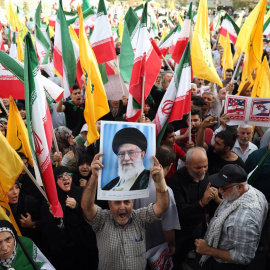 Un iraní sostiene un retrato del líder supremo iraní, el ayatolá Alí Jamenei, entre banderas nde Irán durante una manifestación en Teherán este martes 24 de junio de 2025.