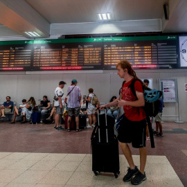 Varias personas junto a sus maletas frente al panel de salidas en la estación de tren de Chamartín, a 14 de agosto de 2024.