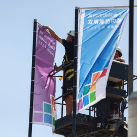 Operarios colocan banderolas en la previa de la IV Conferencia Internacional sobre la Financiación para el Desarrollo, en Sevilla.