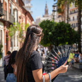 Una mujer se abanica mientras pasea en Sevilla el 5 de julio de 2024.