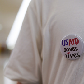 Un exfuncionario federal lleva una insignia de "USAID Salva Vidas" durante una sentada en la oficina de la senadora Susan Collins en Washington por los despidos de federales