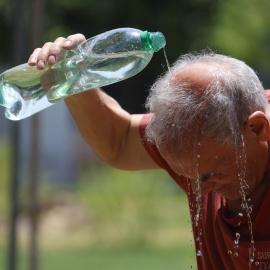Un hombre se refresca con agua de una botella en la calle en Córdoba a 43ºC, en mitad de la ola de calor.