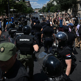 La policía antidisturbios serbia llega para retirar las barricadas erigidas durante una protesta, mientras los manifestantes antigubernamentales alzan las manos en Belgrado el 30 de junio de 2025.