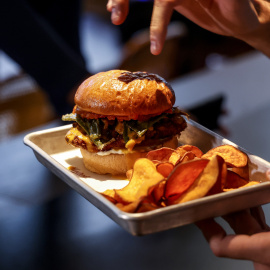 Una persona sostiene una hamburguesa en una bandeja durante la presentación de las novedades de los actos de entrega de la 34ª edición de los Premios Rei Jaume I 2022,