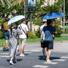 Personas al lado de un termómetro que marca 47 grados de temperatura en Sevilla, Andalucía