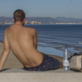Un chico tomando el sol en la playa de Valencia