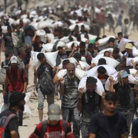 Grupo de palestinos cargando con sacos en Gaza