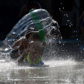 Varios niños se refrescan este lunes en un parque la ciudad cántabra de Torrelavega.