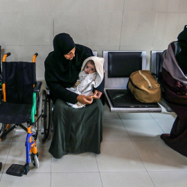 Mujeres palestinas esperan abatidas junto a su equipaje antes de partir de Gaza hacia Egipto para recibir atención médica adecuada.