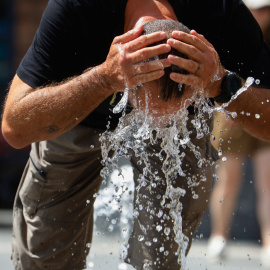 Un hombre se refresca en una fuente en Córdoba (Andalucía).