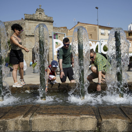 Una familia se refresca en una fuente en Plasencia.