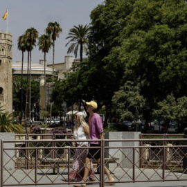 Turistas caminan con la Torre del Oro de fondo en Sevilla durante la ola de calor.