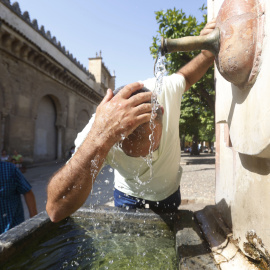Un turista se echa agua en la cabeza de una fuente en el Patio de los Naranjos de la Mezquita Catedral de Córdoba, este pasado martes.