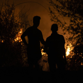Dos personas observan la evolución del incendio forestal en A Rúa (Ourense), a 16 de agosto de 2025.