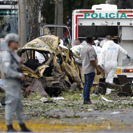 Integrantes de la Dirección de Investigación Criminal e Interpol (DIJIN) inspeccionan un vehículo afectado tras una explosión en inmediaciones de la Escuela Militar de Aviación Marco Fidel Suárez este jueves, en Cali (Colombia).