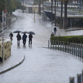 Varias personas se protegen de la lluvia en Sevilla.