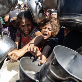Palestinos hacen cola para recibir una comida de una cocina que proporciona alimentos gratuitos a las personas desplazadas en Khan Yunis.