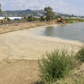 Una màquina retroexcavadora treballant a la bassa d'aigua al costat de les obres del Pla de Balasc, a Santa Susanna (Maresme).