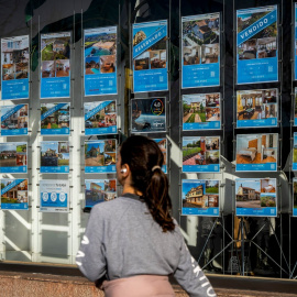 Una mujer pasa junto a una inmobiliaria en Santander.