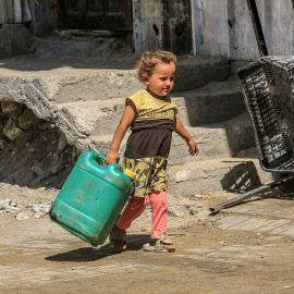 Una niña palestina transporta un bidón de agua en Jan Yunis.
