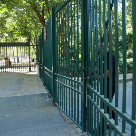 Un empleado de seguridad cierra la puerta de acceso al parque en Sevilla.