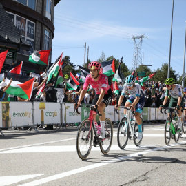 Varios ciclistas pasan por una zona con protestas propalestinas durante la 20ª etapa de la Vuelta Ciclista