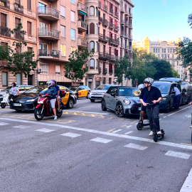 Diversos vehicles esperen a la calçada central i al carril bici del carrer Aragó de Barcelona abans que el semàfor es posi verd