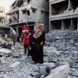 Varios palestinos buscan entre los escombros de un edificio tras un ataque israelí.