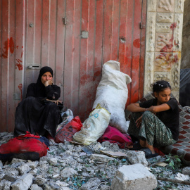 Dos mujeres palestinas con sus enseres después de que su casa fuera alcanzada por un ataque aéreo israelí, en el campo de refugiados de al-Shati (Playa), en Ciudad de Gaza.