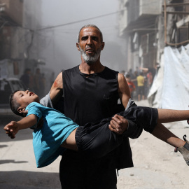 Un hombre palestino lleva en sus brazos a un niño herido por un bombardeo de Israel en Cuidad de Gaza.