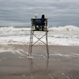 Dos personas sentadas en la silla del socorrista en una playa de Queens
