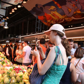 Una dona fa una fotografia a una parada de fruita de la Boqueria