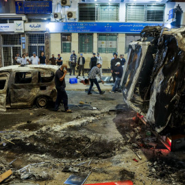 Personas observan vehículos incendiados durante una manifestación liderada por jóvenes.