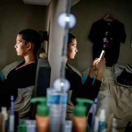Una joven en su habituación con su móvil.