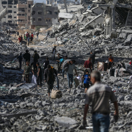 Palestinos caminan por una calle entre los escombros. EFE/ Mohammed Saber