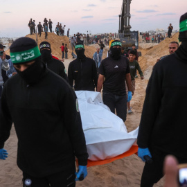 La gente observa cómo militantes de Hamás transportan un cadáver recuperado de un túnel en una zona al norte de Jan Yunis, en el sur de la Franja de Gaza, el 28 de octubre de 2025.