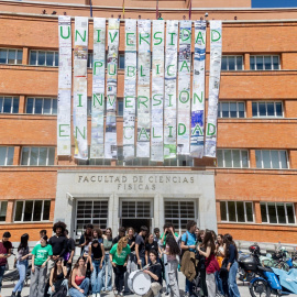 Alumnos y profesores cuelgan un mural de la fachada de la Facultad de Físicas de la Universidad Complutense de Madrid.