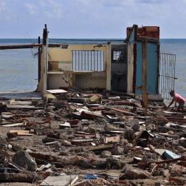 Personas caminan frente a una casa destruida, en Guamá, Santiago de Cuba.