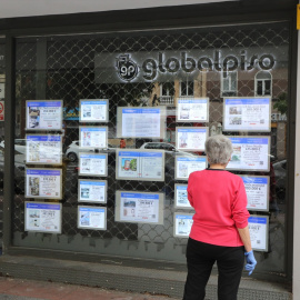 Una mujer echa un vistazo a las ofertas de una agencia inmobiliaria, en una imagen de archivo.