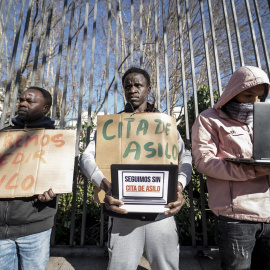 Varios solicitantes de protección internacional sujetan pancartas durante una concentración.
