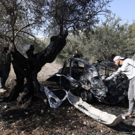 Palestinos observan los restos de un vehículo en el lugar donde tres palestinos fueron asesinados por las fuerzas israelíes en la aldea de Kafr Qud, en la Cisjordania ocupada. (28/10/2025)