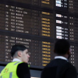 Varios empleados del aeropuerto Bruselas-Zaventem pasan junto a un panel informativo.
